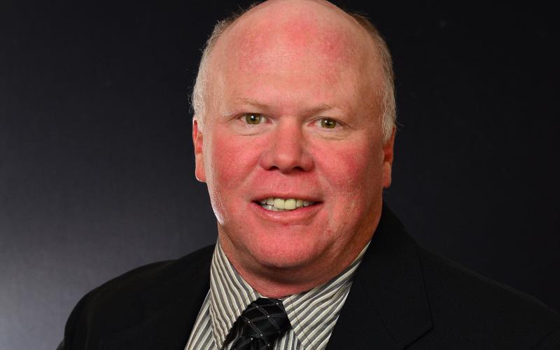 A man in a suit and tie smiles for a portrait