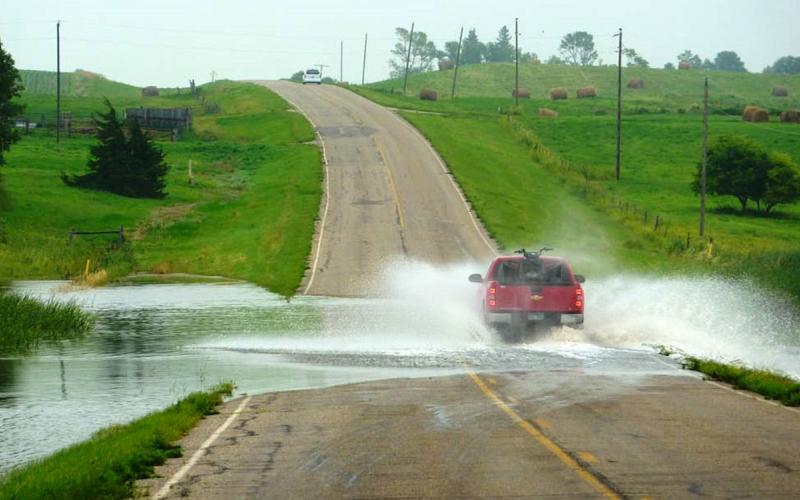 Flood waters obstructing a paved country road.