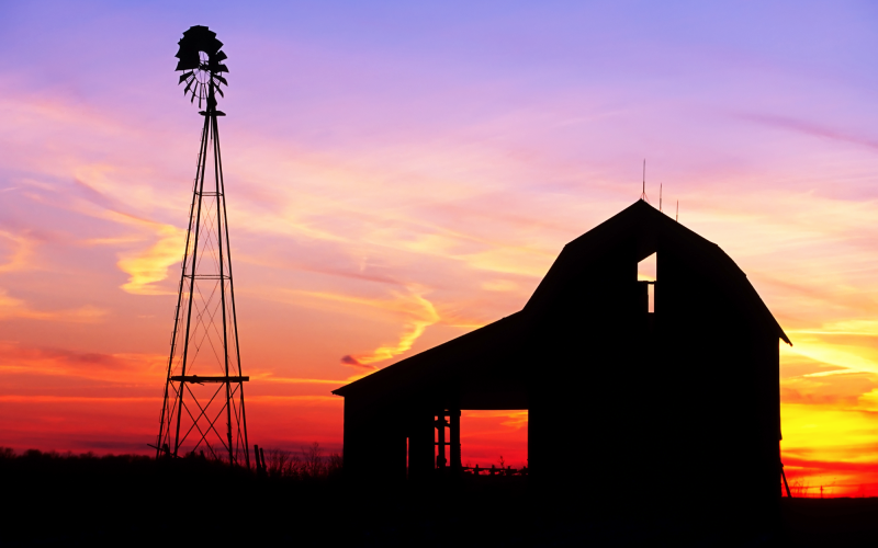 Old barn and windmill with the sunset in the background