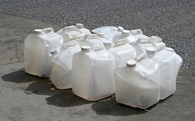 Several damaged plastic pesticide containers grouped together on a driveway.
