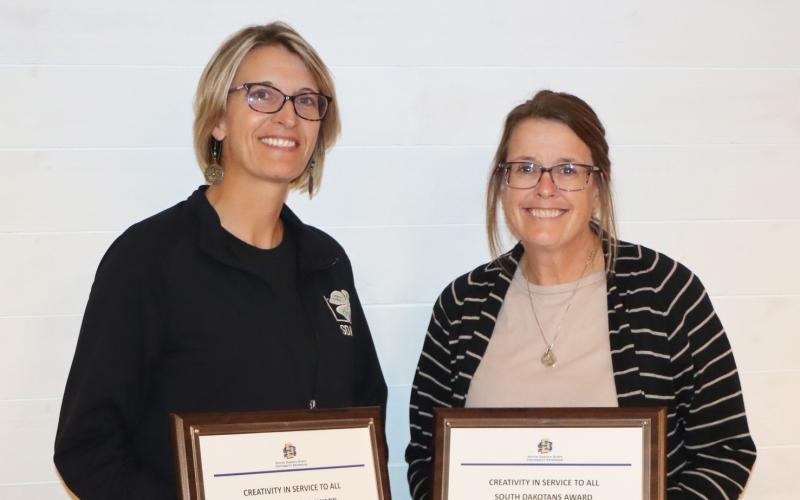 Two women smile for the camera with their plaques