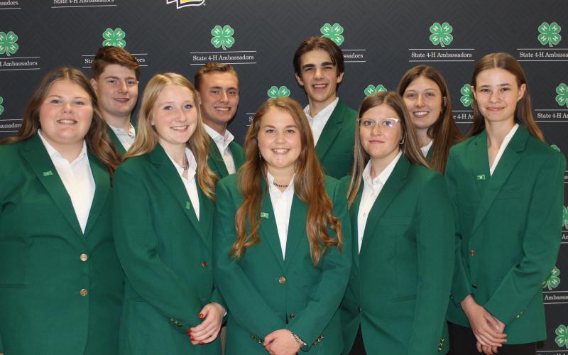 A group of people in green jackets smile for the camera