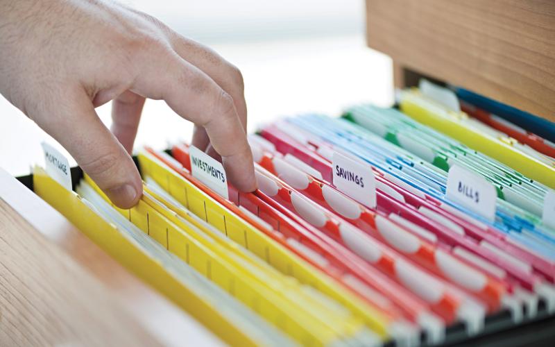 A hand picking a file in a file cabinet