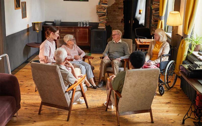 : A group of older adults gathered in a circle for a mental health support session.