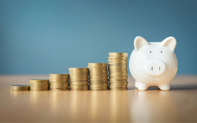 A piggy bank with stacks of coins next to it.