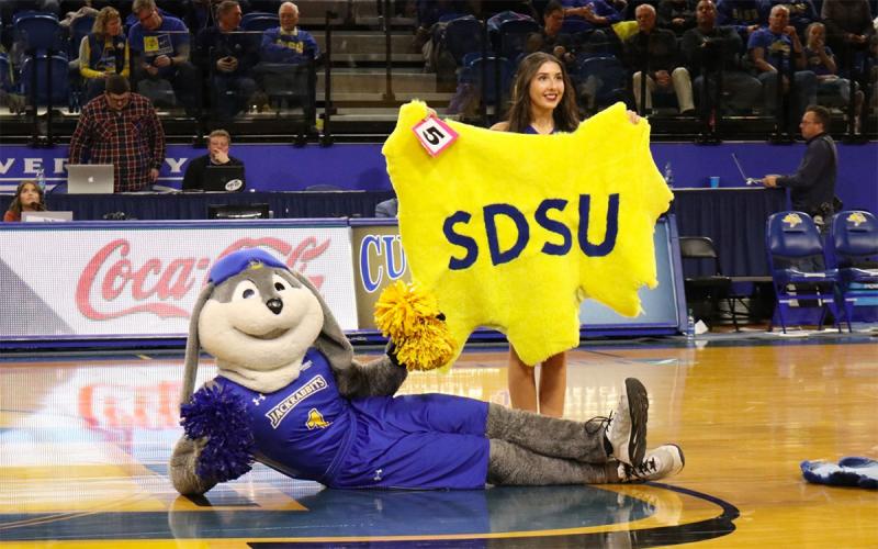 SDSU cheerleader holding a yellow lamb pelt with the SDSU mascot