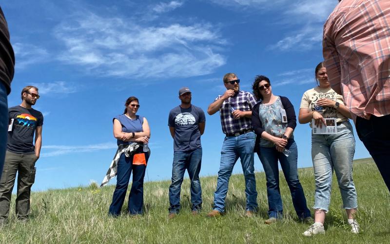 A group of people stands in a pasture