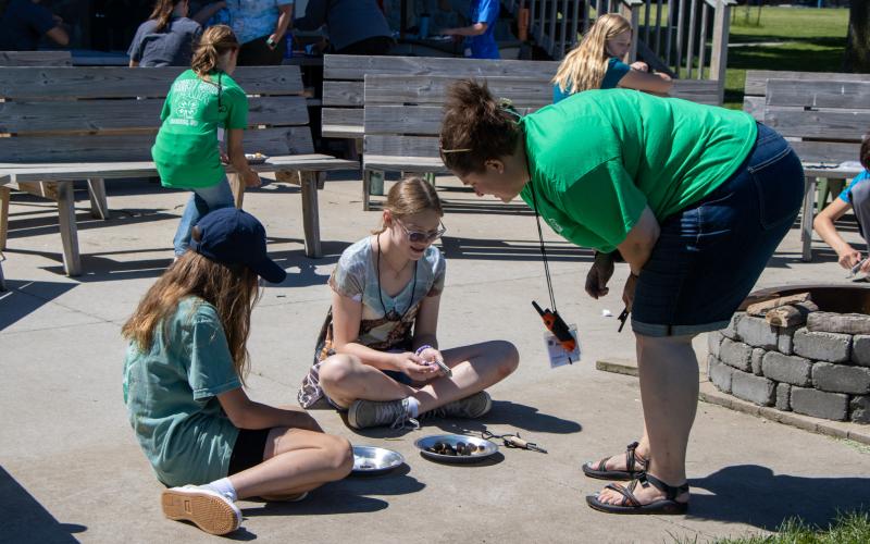 A camp chaperone talking to two campers at summer camp