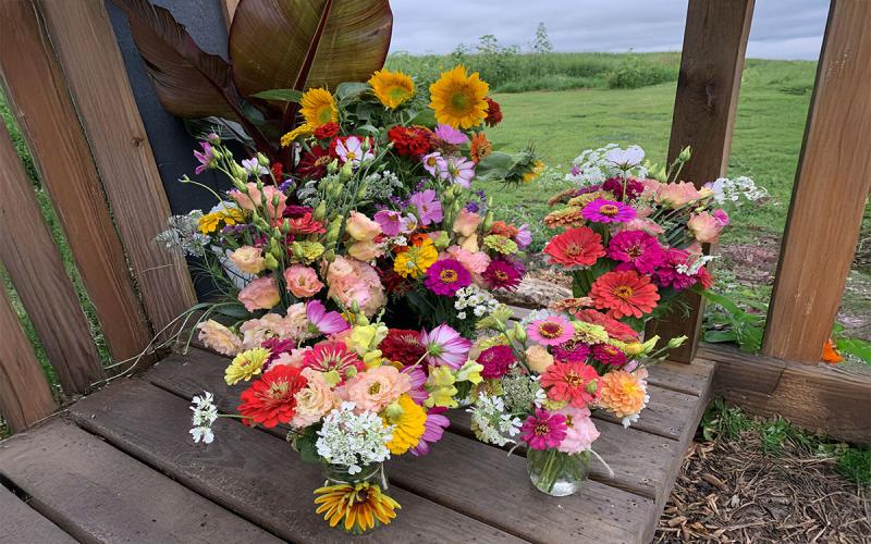 A variety of cut flower arrangements displayed on an outdoor deck.