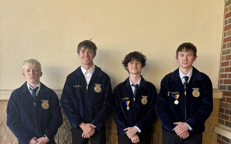 Four teenage boys in matching blue FFA jackets pose in front of a wall