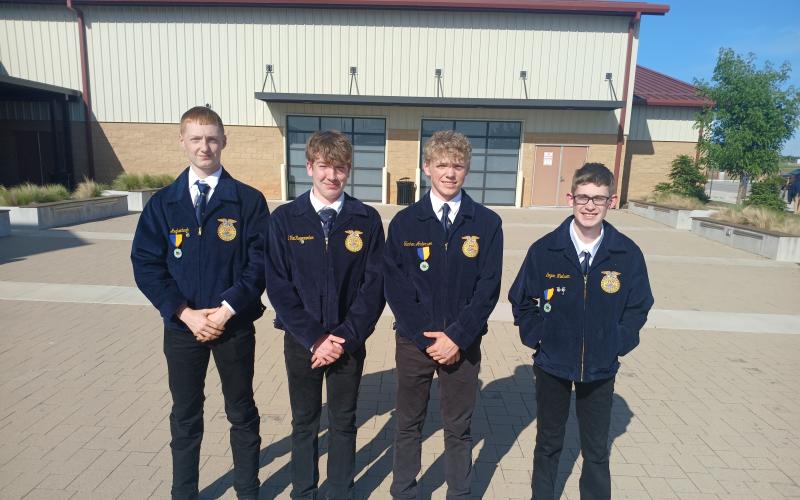 Four teenage boys in matching blue FFA jackets pose outside
