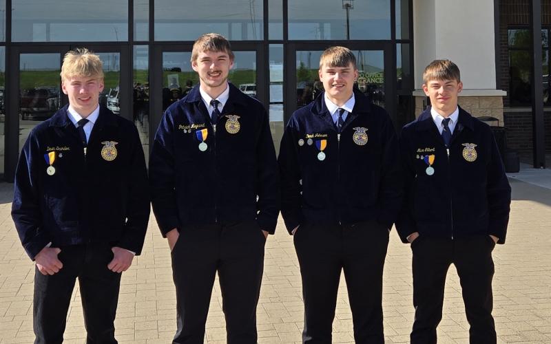 Four teenage boys in FFA jackets stand outside a building