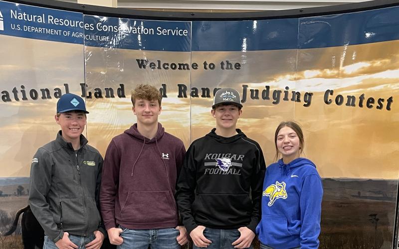 Four youth in hoodies stand in front of a display that says "Welcome to the National Land and Range Judging Contest"