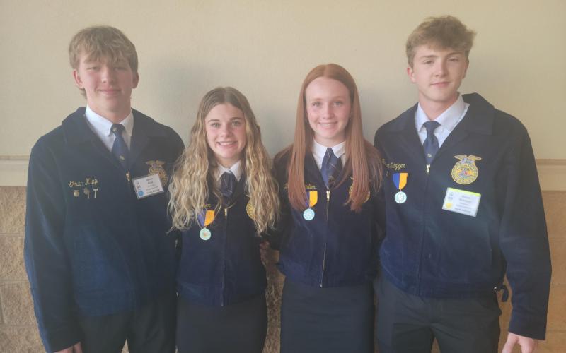 Four youth in FFA jackets stand for a team photo