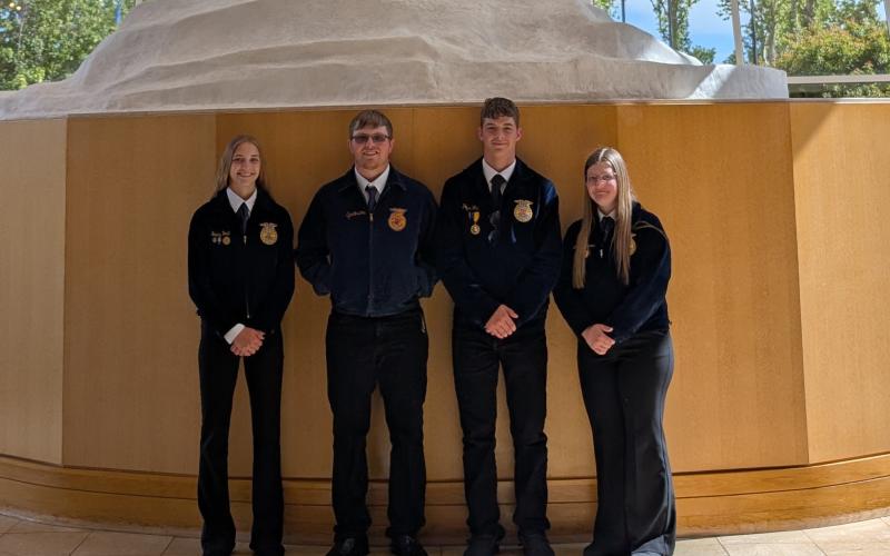 Four youth in FFA jackets smile for a team photo