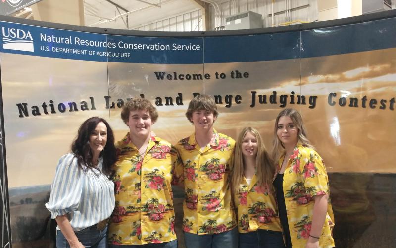 four youth in matching Hawaiian shirts smile with their coach for a team photo