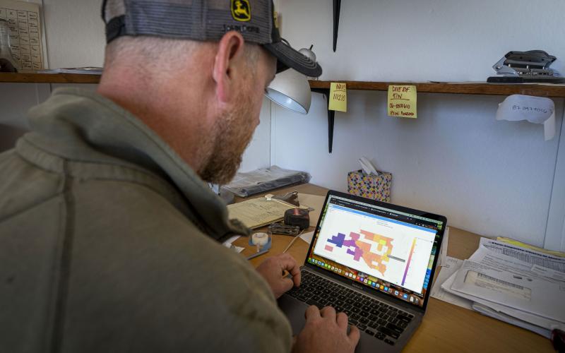 Landowner viewing information on a laptop computer in a farm office.