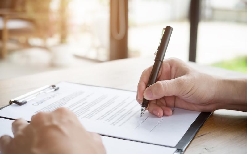 Person signing a contract with a black pen