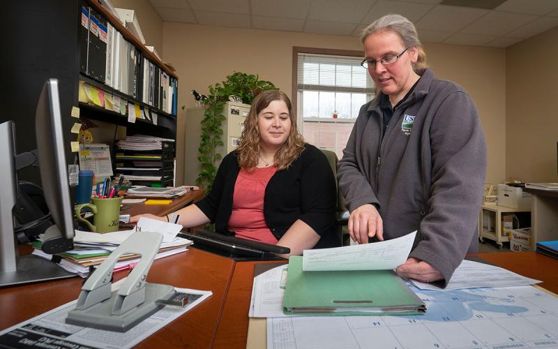 USDA agent and producer reviewing paperwork at a desk.
