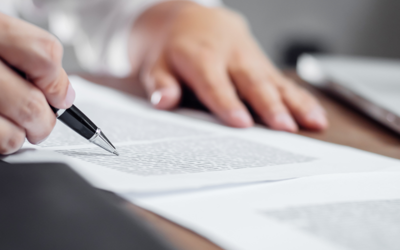 Hands reviewing a document and pointing to a certain section with a pen