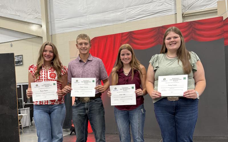 Four youth smile with certificates