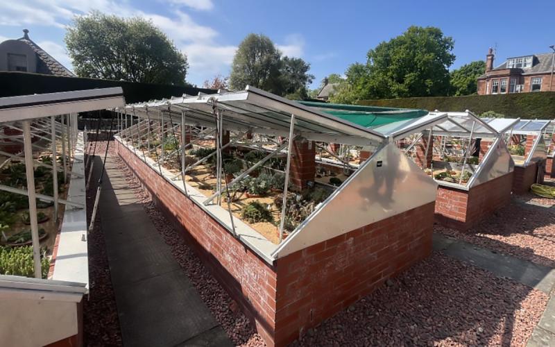 Raised-bed style cold frame structures with brick frames and glass lids.