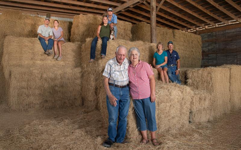 Three generations of a family farm gathered in a barn.