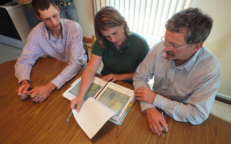 Ranchers reviewing farmland maps with a consultant.