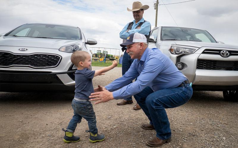 Rancher greeting grandson in a farm driveway.