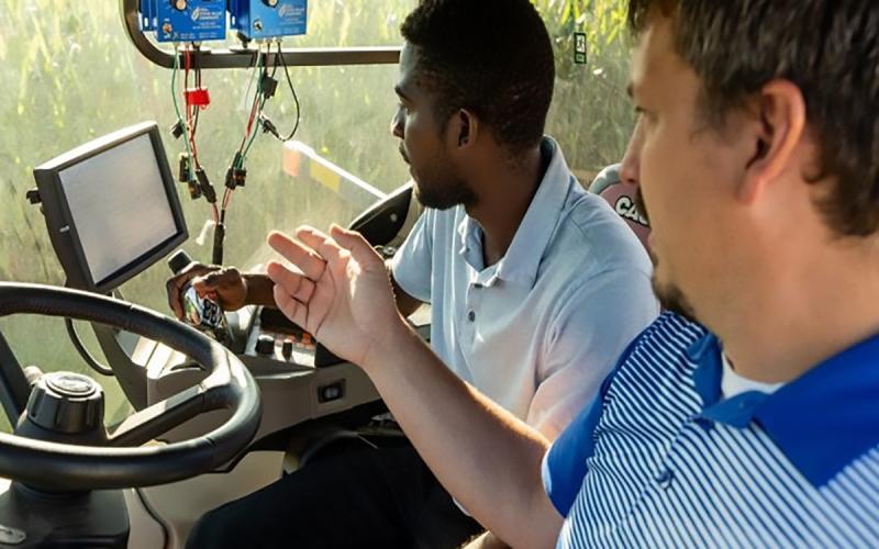 Instructor and student in cab of tractor looking at a monitor.