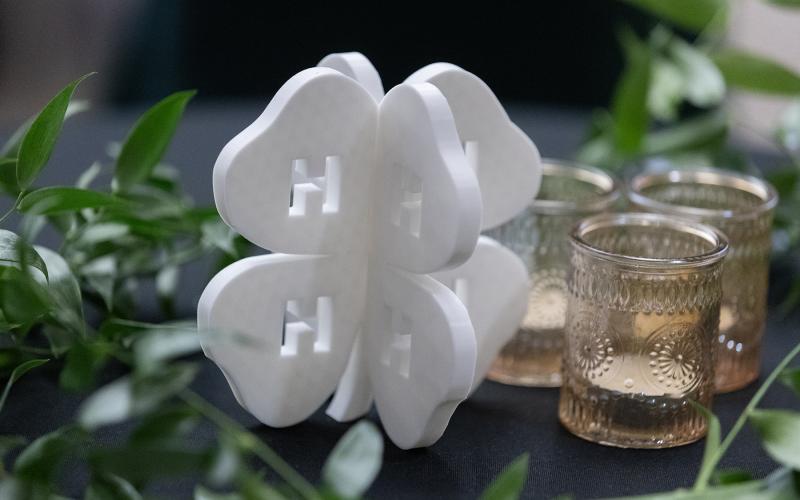A white, four-dimensional 4-H clover sits next to votive candles as a table centerpiece
