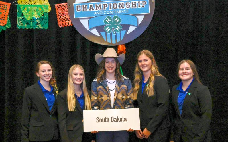 Five youth smile for the camera holding a sign that says "South Dakota"
