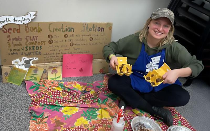 A young master gardener setting up a “make your own seed bomb” station at a seed swap.
