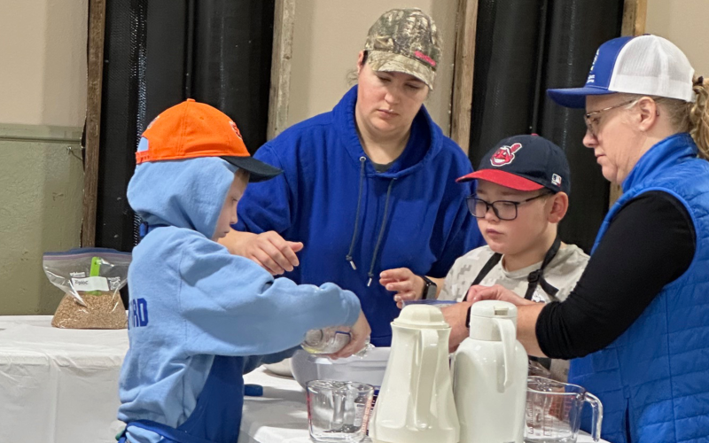 Two adult 4-H volunteers assisting two 4-H members with a project
