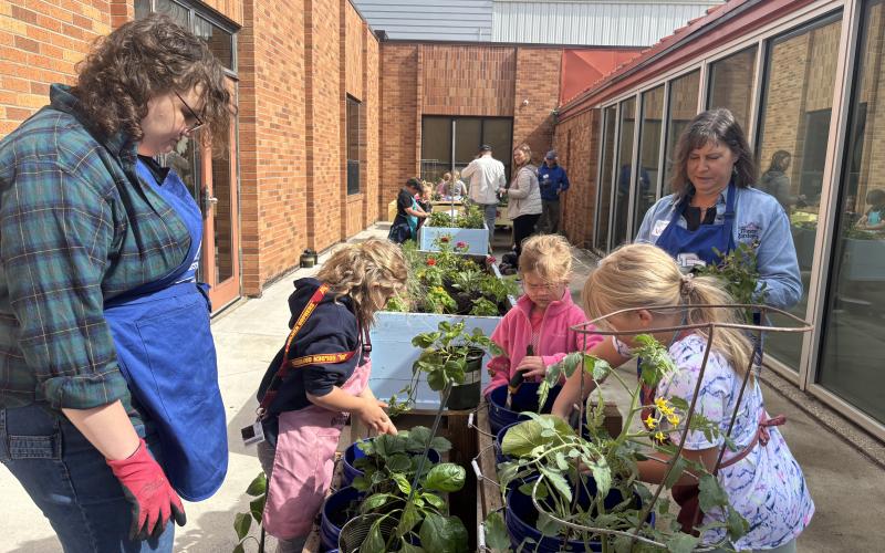 Youth and two adult helpers work with plants in box planters