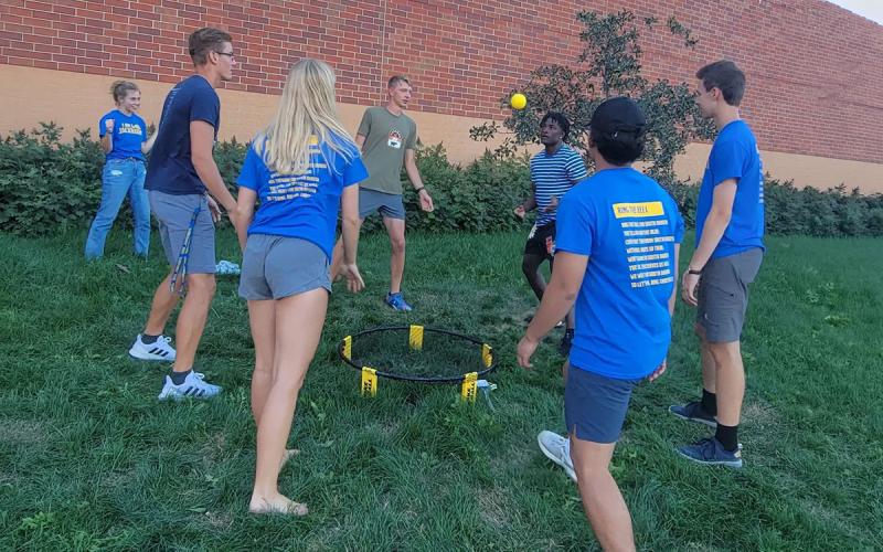 Group of young adults playing hacky sack outside the SDSU Miller Wellness Center.
