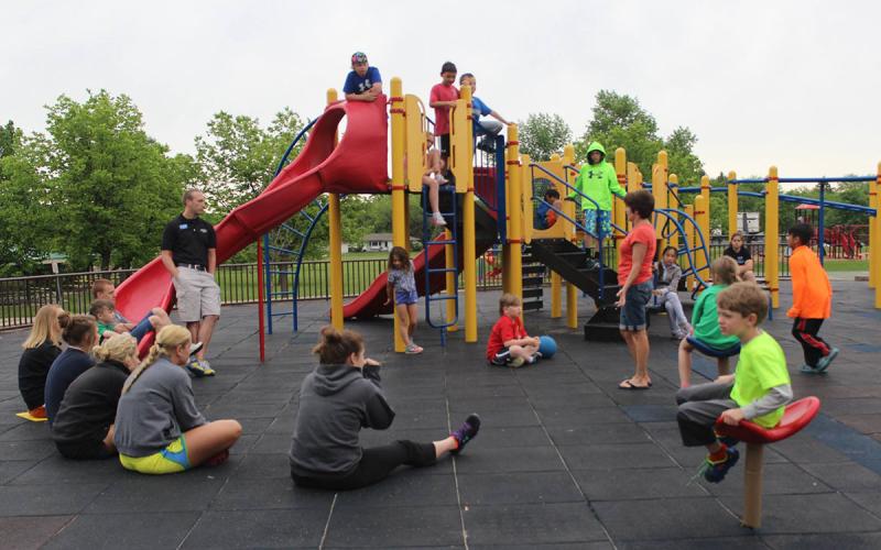 Group of young adults and children gathered at a playground.