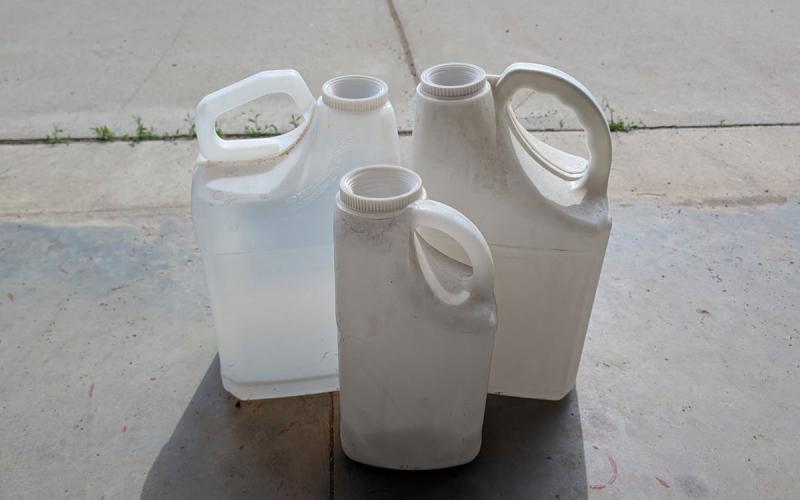 Cleaned, emptied pesticide containers on a concrete workshop floor.