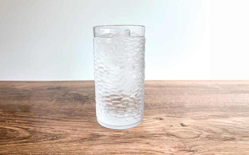 Glass of water sitting on a hardwood table.