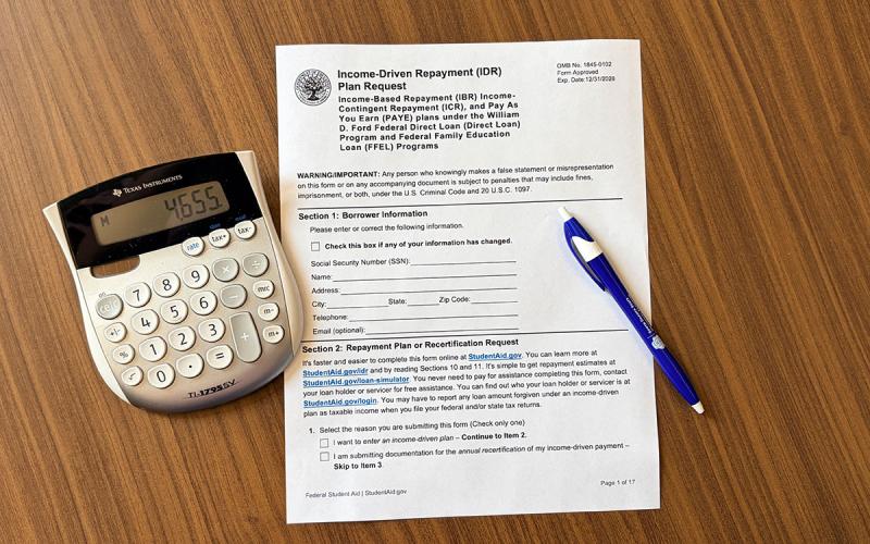 A pen, calculator, and loan application on a table.