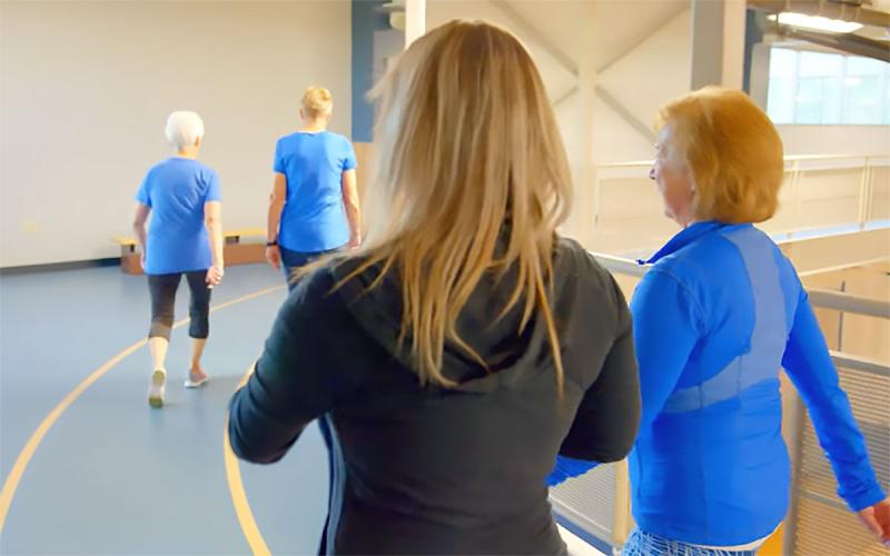 Group of women walking together on an indoor track.