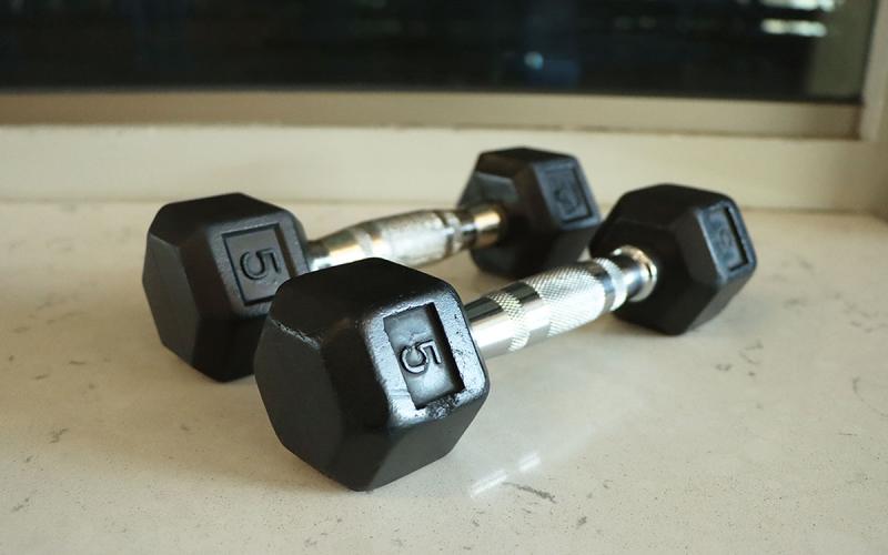 Hand weights resting on a bench inside a gymnasium.