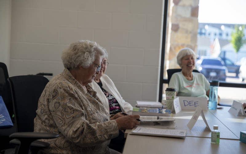Three older adults smiling while sitting around a table during a training.